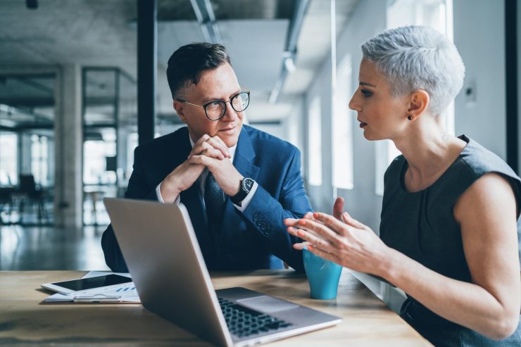 Two colleagues discussing work in front of a laptop