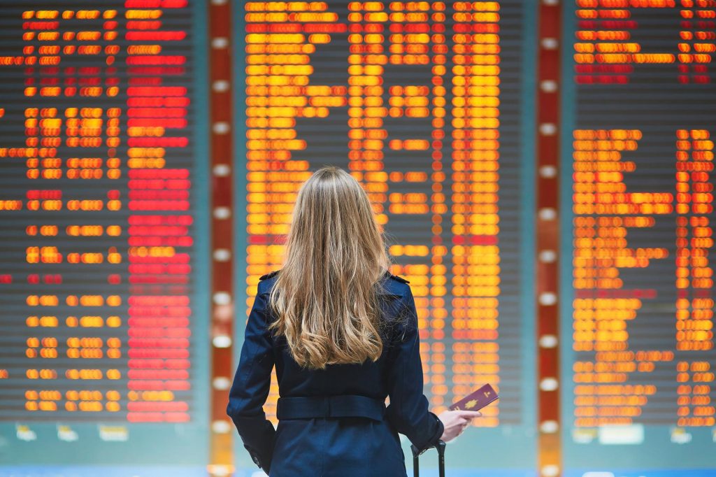 Young woman in international airport Young woman in international airport looking at the flight information board, checking her flight